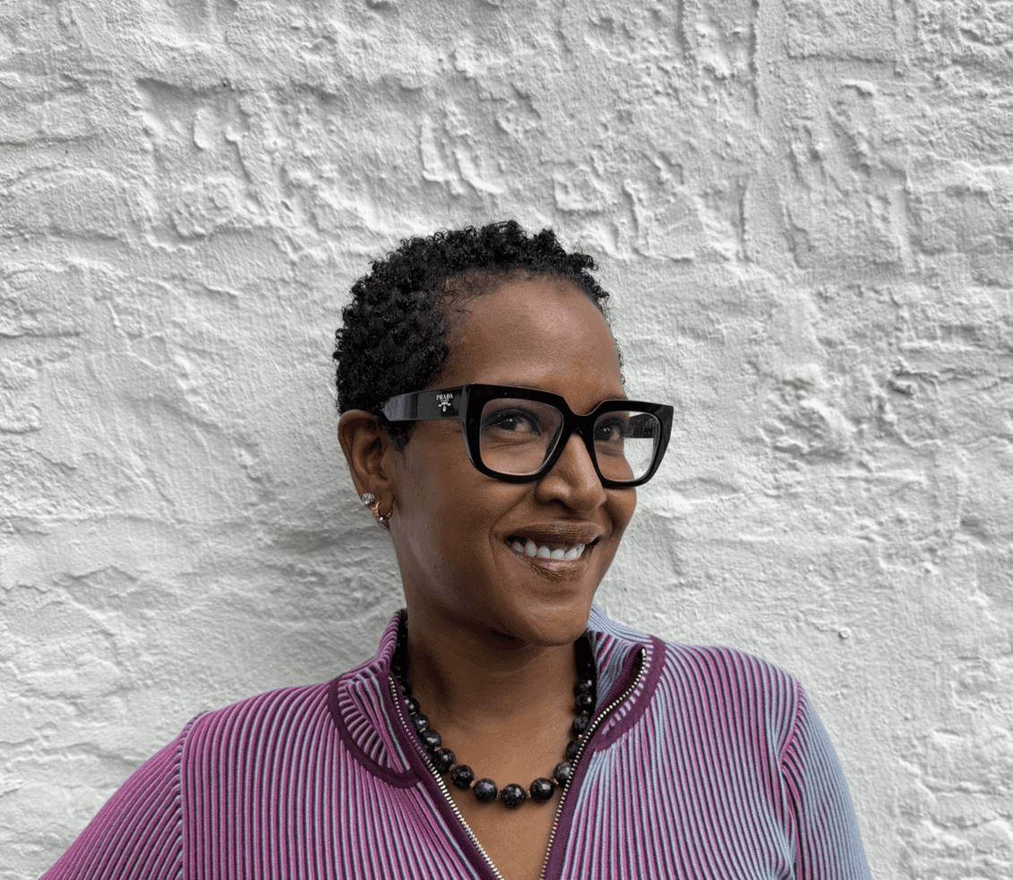 Krystal K. Thompson, founder of KUPONYA, against a whitewashed brick wall.